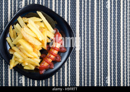 Draufsicht auf das russische Nationalgericht - Bratwurst mit Tomaten-Ketchup und Pommes frites als Beilage Stockfoto