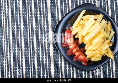 Draufsicht auf das russische Nationalgericht - Bratwurst mit Tomaten-Ketchup und Pommes frites als Beilage Stockfoto