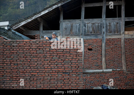 Ein Bauer sein privates Haus mit Ziegeln und Holz in einem kleinen abgelegenen Dorf in den Bergen von West-China. Stockfoto