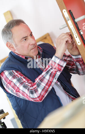 ältere männliche Schlosser Befestigung Türgriff ein Zuhause Stockfoto