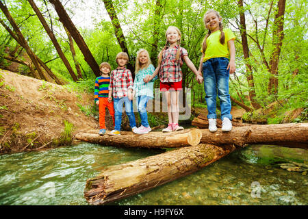 Glückliche Freunde stehen Hand in Hand auf Log-Brücke Stockfoto