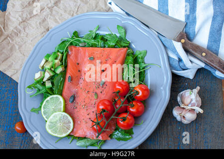 Gesalzener Lachs mit Kräutern, Tomaten und Salat auf einem Holzbrett. Liebe für eine gesunde Rohkost-Konzept Stockfoto