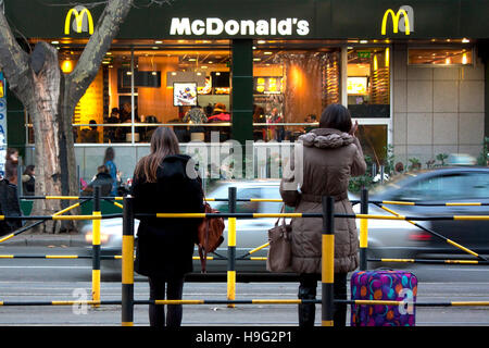 Belgrad, Serbien - 18. November 2016: Zwei junge Frauen stehen an der Bushaltestelle gegenüber von McDonald's-restaurant Stockfoto