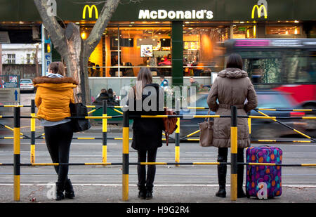 Belgrad, Serbien - 18. November 2016: Drei junge Frauen stehen an der Bushaltestelle gegenüber von McDonald's-restaurant Stockfoto