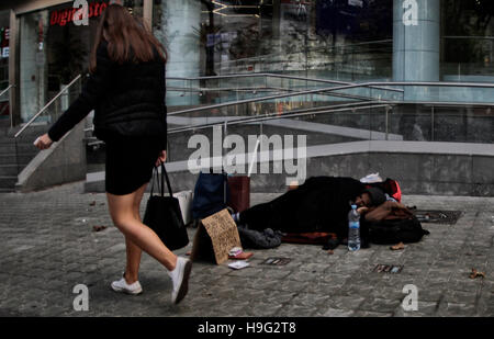 Eine arme Frau bittet um Geld in eine Einkaufsstraße in Barcelona Stockfoto