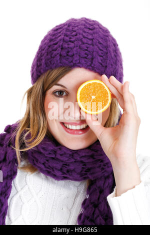 Junge Frau tragen Winterkleidung, hält eine Orange vor ihrem Auge Stockfoto