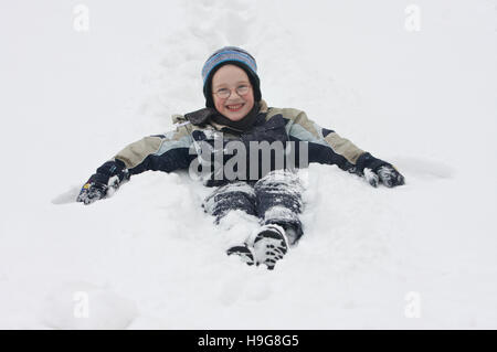 Sieben-Jahr-alter Junge sitzt im Schnee Stockfoto