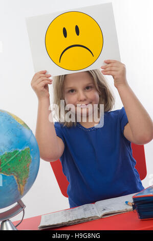 Mädchen an ihrem Schreibtisch, trauriger Smiley, symbolisches Bild für Probleme in der Schule Stockfoto