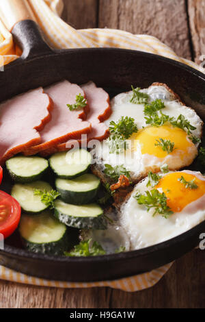 Hausgemachtes Frühstück: Spiegelei mit Schinken und frischem Gemüse in einer Pfanne Nahaufnahme. vertikale Stockfoto