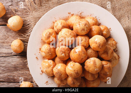 Türkischer Lokma Krapfen mit Honig und Zimt Nahaufnahme auf einer Platte. Horizontale Ansicht von oben Stockfoto