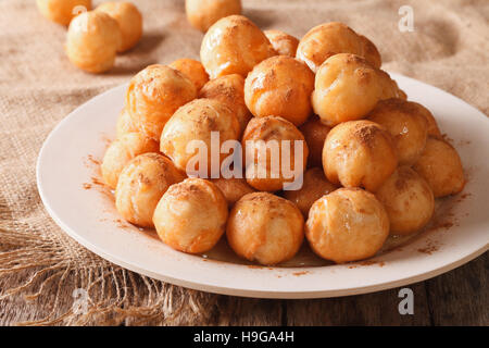 Türkischer Lokma Krapfen mit Honig und Zimt Nahaufnahme auf einer Platte. horizontale Stockfoto