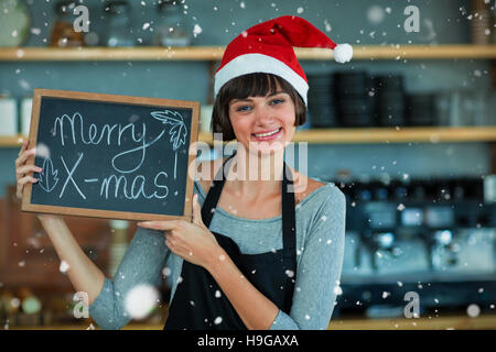 Zusammengesetztes Bild Porträt der Kellnerin mit Schiefer mit merry x-mas-text Stockfoto