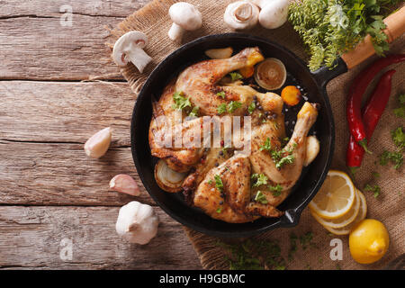 Fried Chicken Tabak mit Kräutern und Knoblauch in einer Pfanne Nahaufnahme heiß. horizontale Ansicht von oben Stockfoto