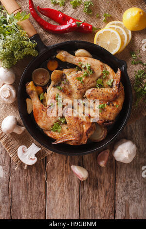 Fried Chicken Tabak mit Kräutern und Knoblauch in einer Pfanne Nahaufnahme heiß. Vertikale Ansicht von oben Stockfoto