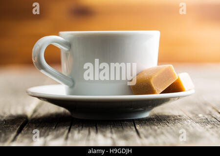 Kaffeetasse und Karamell Bonbons auf Holztisch. Stockfoto