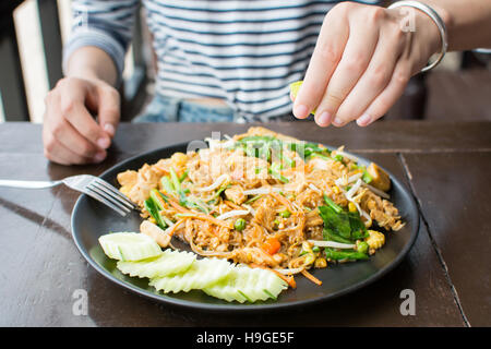 Weibliche Hand drückte Kalk auf Pad Thai Restaurant Stockfoto