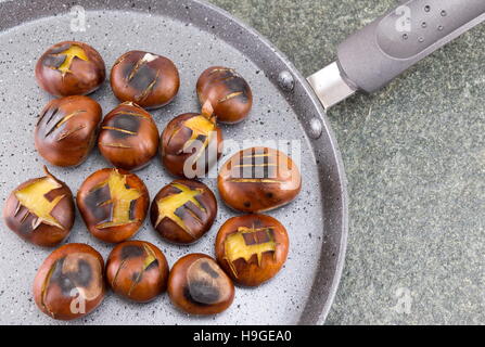 Gebratene Kastanien auf einem Stein Kochen Pfanne Stockfoto