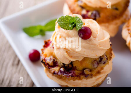 Hausgemachte Herbst Cranberry-Kürbis-Cupcakes mit Frischkäse Icingon rustikalen Holztisch Stockfoto