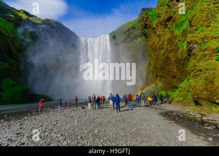 SKOGAR, Island - 12. Juni 2016: Blick auf den Skogafoss Wasserfall, mit Touristen und Regenbogen, am Fluss Skoga in Südisland Stockfoto