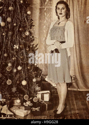 Frau, Annahme von Geschenken unter dem Weihnachtsbaum. Alte gelbe Fotopapier. Stockfoto