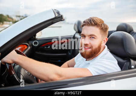 Porträt von schönen jungen lächelnden Mann sitzt in seinem eigenen Auto Stockfoto