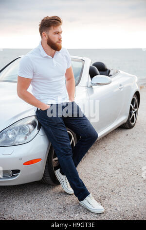 In voller Länge Portrait von einer selbstbewussten bärtiger Mann stützte sich auf seine Luxus-Auto Stockfoto