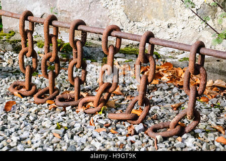 Rostige Ketten auf einer Eisenstange verwendet, um aus einem Stein Weg. Stockfoto