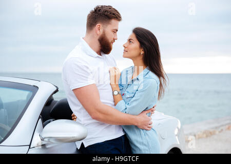 Junge schöne junge Paar umarmt beim stehen in der Nähe von Auto am Meer Stockfoto