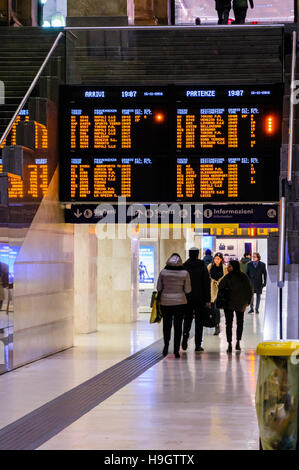 Passagiere Fuß unter dem Zeitplan Brett am Bahnhof Milano Centrale, Mailand, Italien. Stockfoto