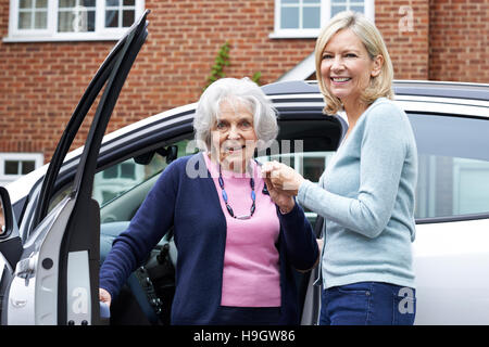 Weibliche Nachbarn geben Senior Woman A Lift im Auto Stockfoto