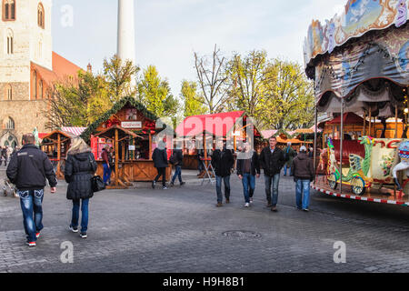 Berlin, Deutschland, 23. November 2016. Die Berliner Weihnachtzeit ist ein deutscher Weihnachtsmarkt rund um den historischen Neptunbrunnen (Neptunbrunnen) hinter Alexanderplatz gelegen. Die festliche hölzerne Marktstände befinden sich zwischen das Rotes Rathaus (Rotes Rathaus) und der Marienkirche. Eine festliche Atmosphäre erfolgt durch Drehorgel Musik, Glühwein, Stände verkaufen Kunsthandwerk, Brot in einer traditionellen Bäckerei und heißen Met gebacken aus Tonkrügen serviert. Besucher genießen eine Eisbahn und das 50 Meter hohe Riesenrad mit traditionellen Gondeln. Kinder genießen Sie Besuche zu den Streichelzoo, Pony zu befreien Stockfoto