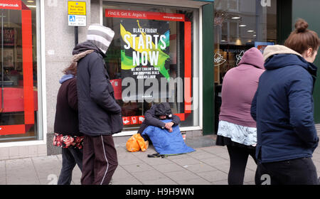 Brighton, UK, 24. November 2016 - Käufer aus einigen frühen Schwarzen Freitag Schnäppchen in Brighton heute als Obdachloser auf dem Bürgersteig bittet Stockfoto