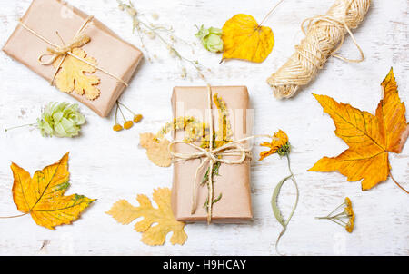 Anordnung von Geschenken und gelbe Blätter auf einem weißen Hintergrund aus Holz. Konzept-Herbst Stockfoto