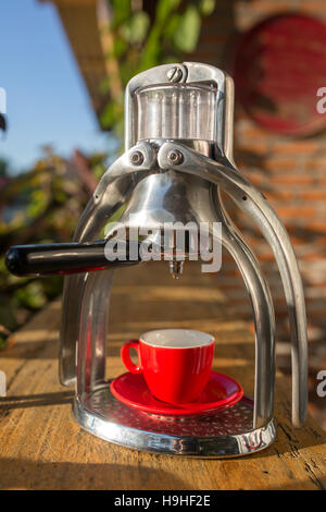 Manuelle Oldschool Espresso Maker Maschine mit einer Tasse auf Holztisch im schönen Morgenlicht Stockfoto