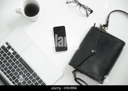 Weißer Schreibtisch mit Tastatur, Handy, Brille, Kaffee, Stockfoto