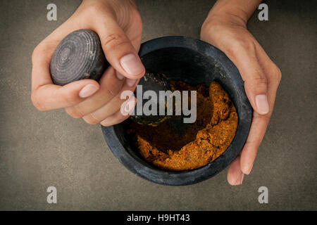 Die Frauen halten Stößel mit Mörtel und und rote Currypaste würzen Stockfoto