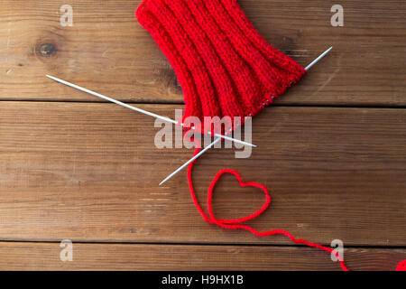 Strickende Nadeln und Faden in Herzform auf Holz Stockfoto