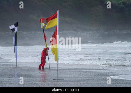 RNLI Rettungsschwimmer legt eine Sicherheitsfahne auf Fistral Strand in Newquay, Cornwall. Stockfoto