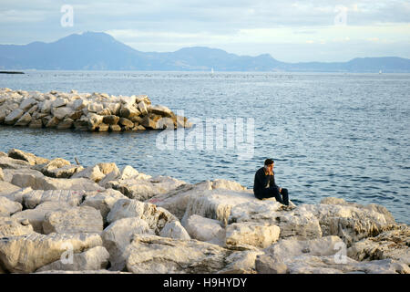 Neapel, Italien, Mann am Telefon, auf den Felsen Stockfoto