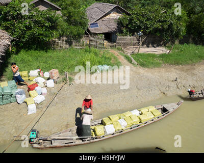 Waren der Verladung in ein kleines Boot für die lokale Verteilung entlang der Nebenflüsse des Flusses Kaladan in Myanmar. Stockfoto