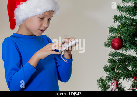 Junge in Santa Cap Weihnachtsbaum mit Weihnachten Spielzeug Stockfoto