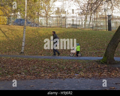 Glasgow Park Szene Vater und Kind unter der Leitung von führen auf Fahrrad Stockfoto