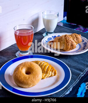 duftendes Frühstück Bagel, Croissant, Bagel, Saft und Milch von der warmen Sonne des Morgens beleuchtet Stockfoto