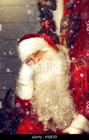 Portrait of Santa Claus. Weihnachtsmann sitzt auf der Treppe in der Nähe der Tür. Stockfoto