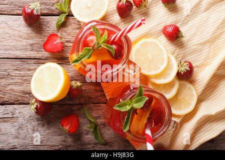 Kalte Erdbeer Limonade mit Minze hautnah in einem Glas auf dem alten Tisch. horizontale Ansicht von oben Stockfoto