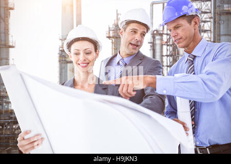 Zusammengesetztes Bild von Geschäftsleuten und eine Frau mit harten Hüte und Holding Blaupause Stockfoto