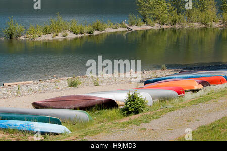 Bunte Kanus aufgereiht am Ufer eines Sees Stockfoto