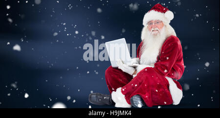 Zusammengesetztes Bild von Santa sitzt und einen laptop Stockfoto