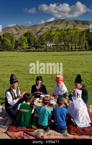 Kasachisch-Familie in traditioneller Kleidung beten vor dem Essen bei einem Picknick in bleibt Kasachstan Stockfoto