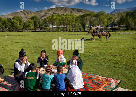 Kasachisch-Familie in traditioneller Kleidung endet ein Gebet vor dem Picknick Essen in Weiden bei bleibt Kasachstan Stockfoto